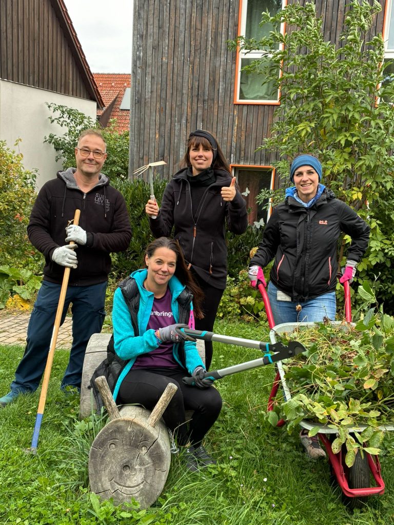 Menschengruppe mit Gartenwerkzeugen auf der Wiese